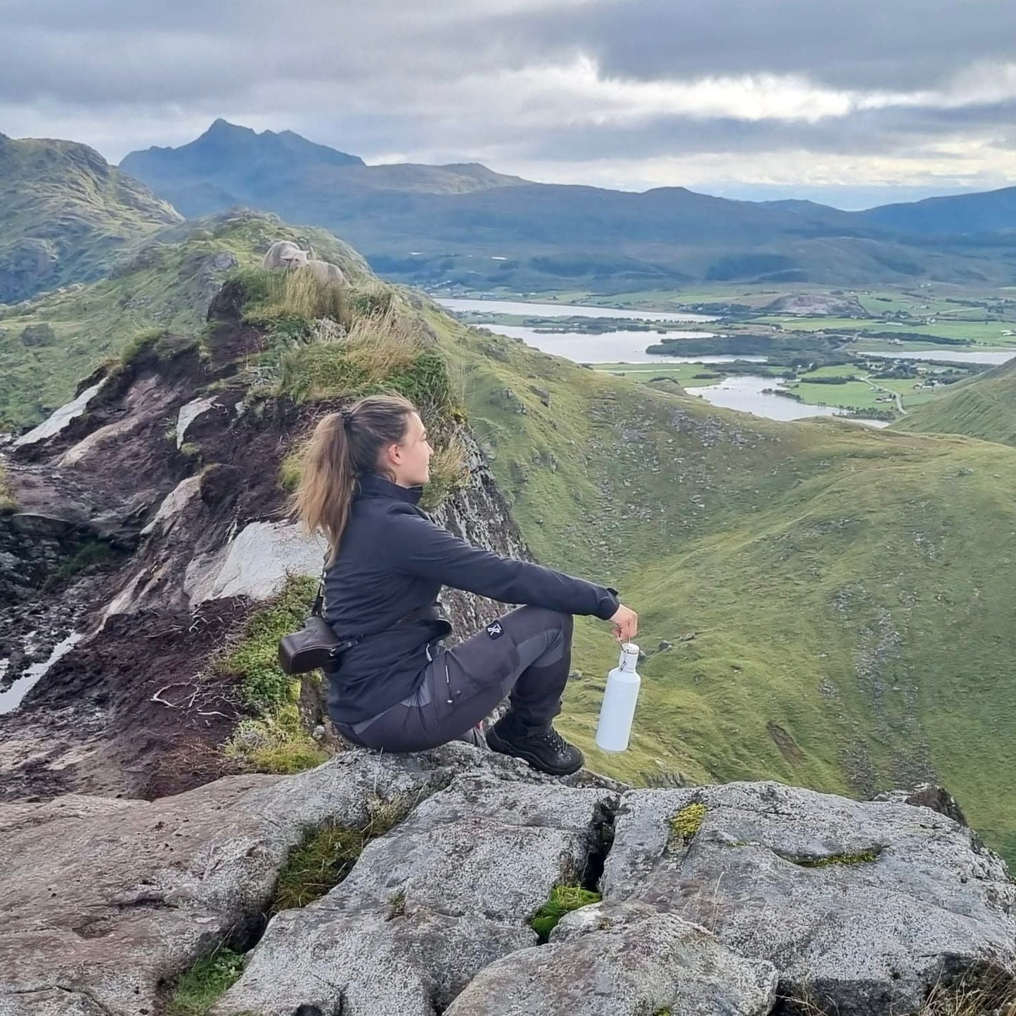 junge frau sitzend auf einem felsen mit der porzellan trinkflasche