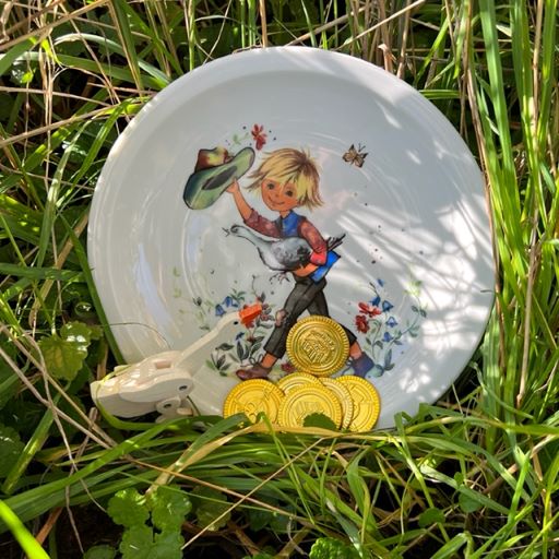 Ein Teller mit Hans im Glück darauf im Gras mit einer Gans.