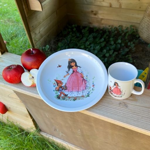 Ein Teller und eine Tasse mit Schnewittchen darauf im Kaufladen mit Äpfeln.