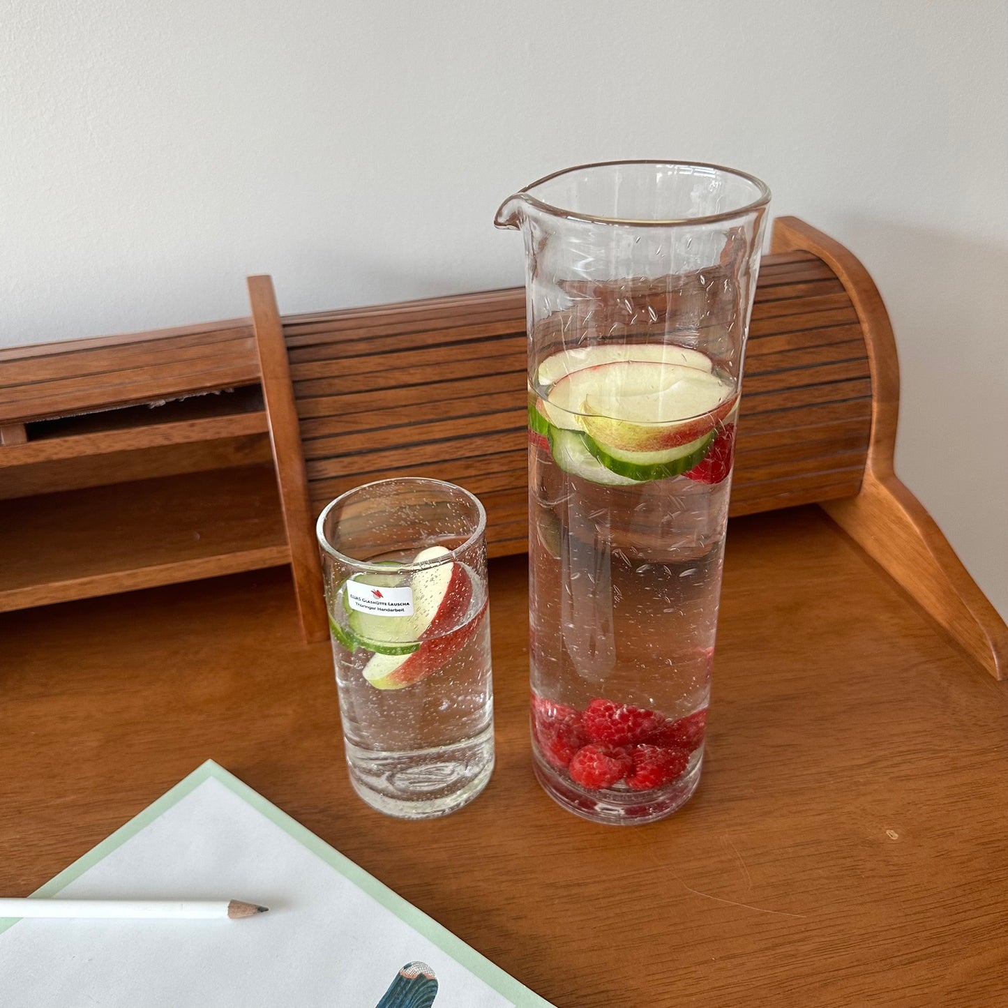 Eine Karaffe aus Altglas neben einem Trinkglas aus Altglas. Mundgeblasen in Lauscha.