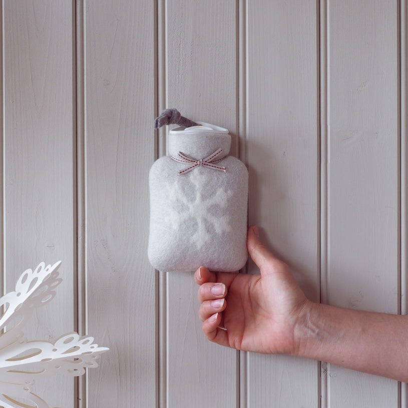 kleine hellgraue waermflasche mit weißem schneeflocke motiv