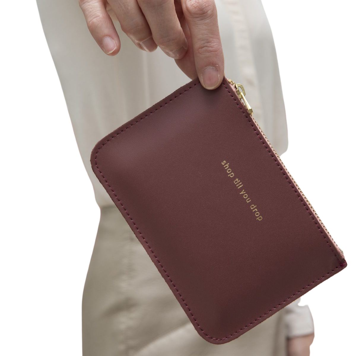 Eine kleine Geldbörse in Altrosa mit goldenem Reißverschluss zwischen zwei Fingern.