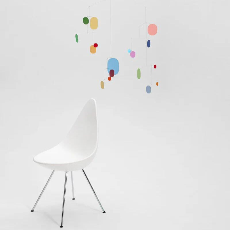 großes buntes mobile mit vielen kleinen bunten blättchen hängend über einem weißen stuhl