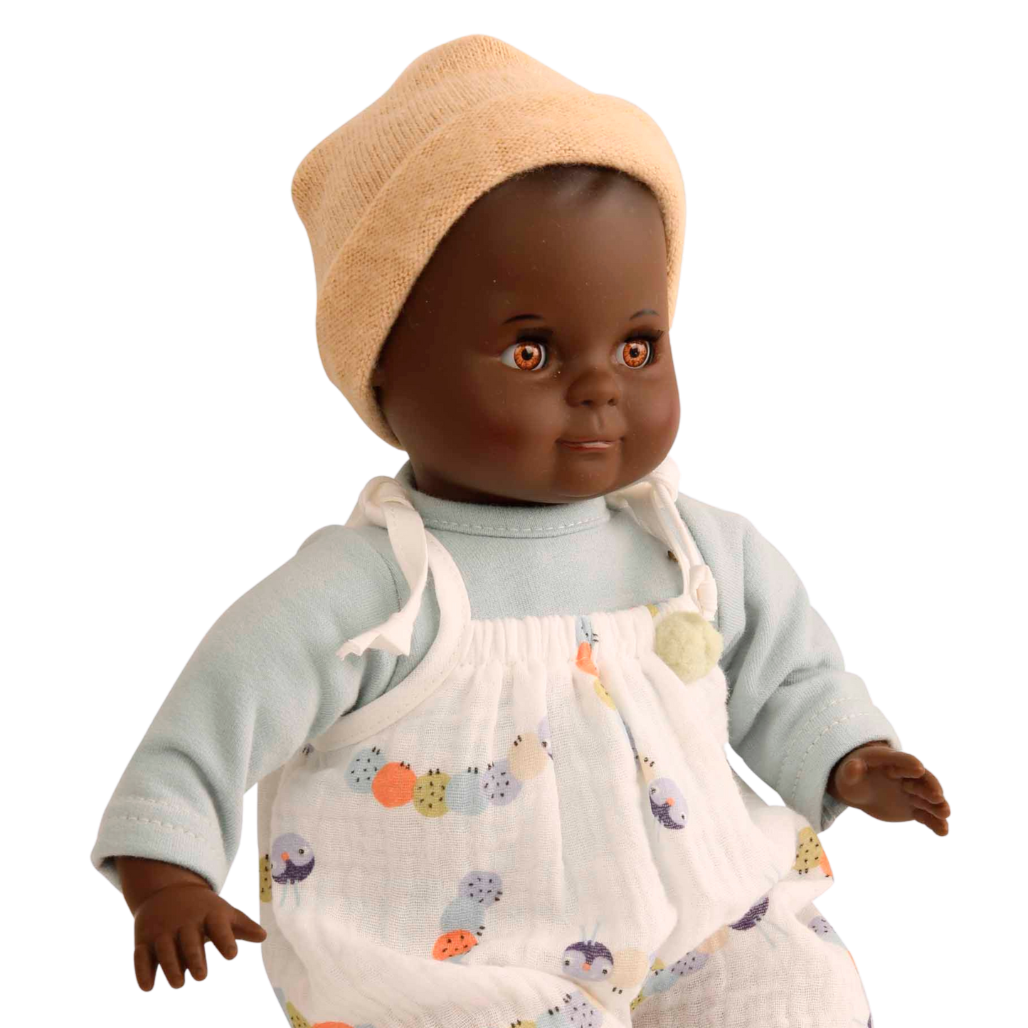 Kleine farbige Puppe mit Schlafaugen und Stoffkörper. Ein weißer Strampler und ein Mützchen.