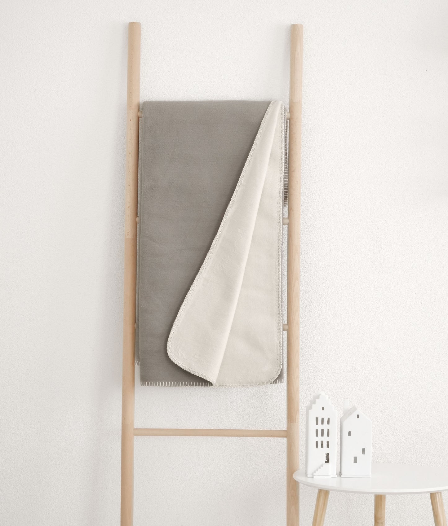 Baumwolldecke zum
Wenden in gau und beige, hängend an einer Leiter.