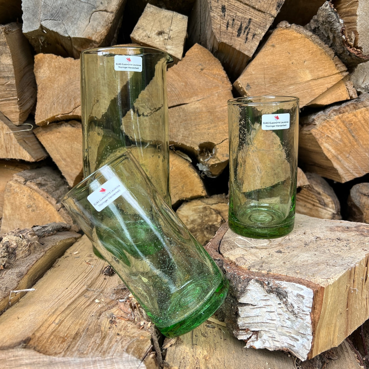 waldglas krug und zwei waldglas glaeser auf einem holzstapel