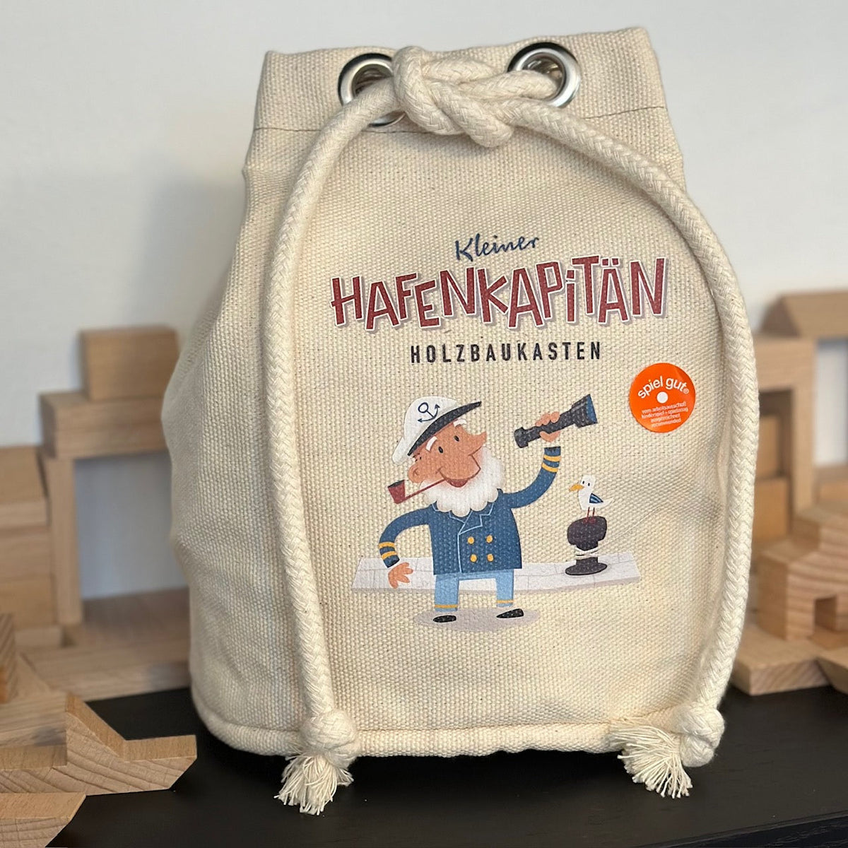 Kleiner Seesack mit einem Kapitän darauf und Holzbausteinen darin.