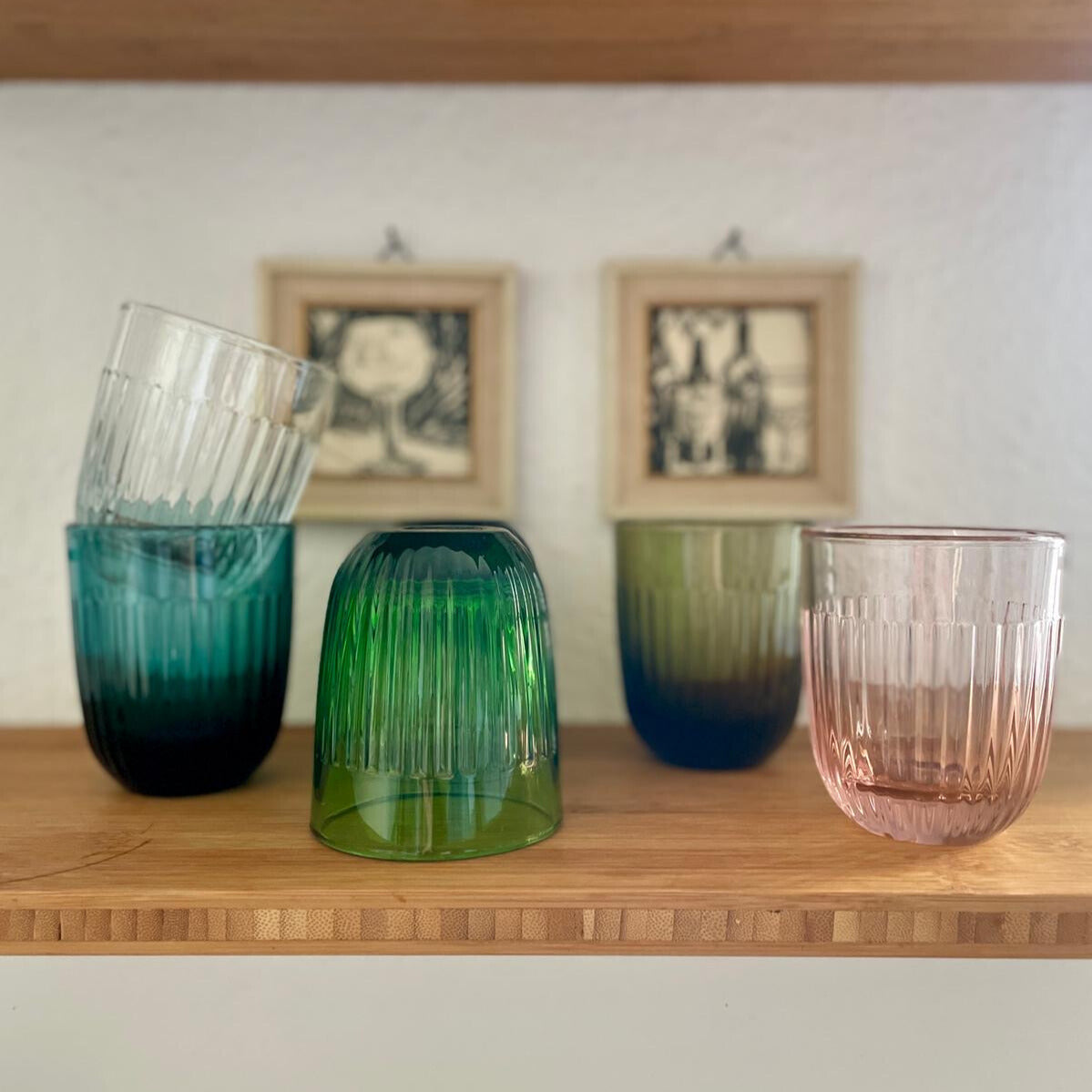 Fünf farbige Gläser aus mechanischem Glas stehen in einem Regal.