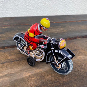 schwarzes Motorrad aus Blech mit Motorradfahrer im roten Anzug und gelben Helm