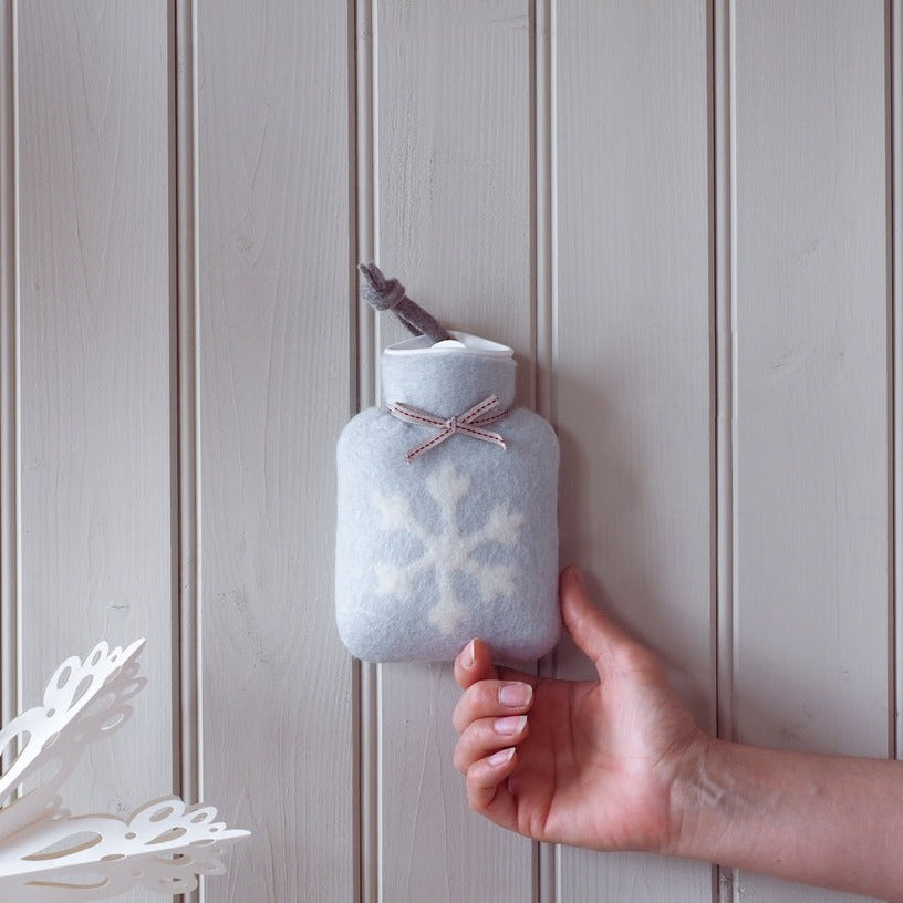 kleine hellgraue waermflasche mit weißem schneeflocke motiv