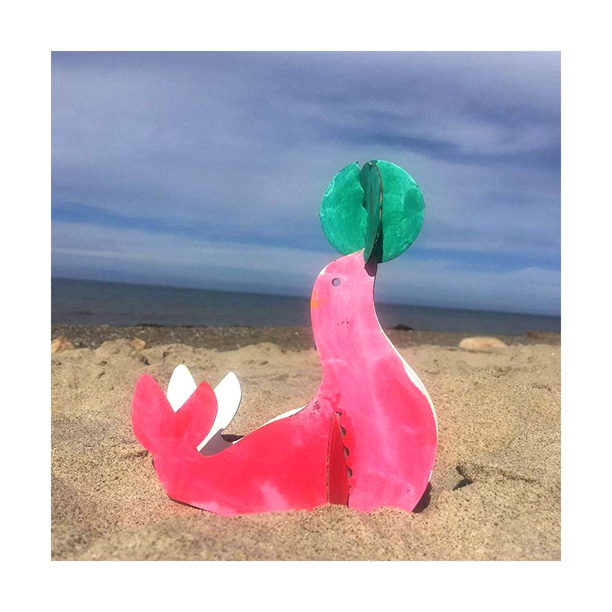 bunt bemalte robbe aus karton am strand dekoriert