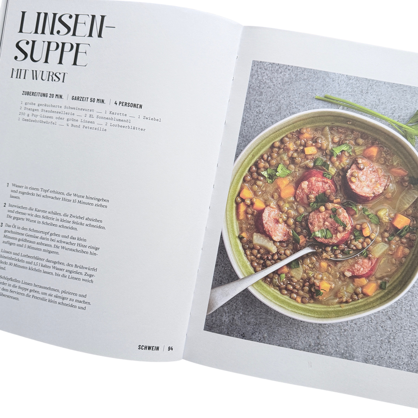 Kochbuch mit Schmortopfgerichten. Seite mit einem Linsensuppen Gericht. Ein Topf mit Linsen und Wurst darin. 