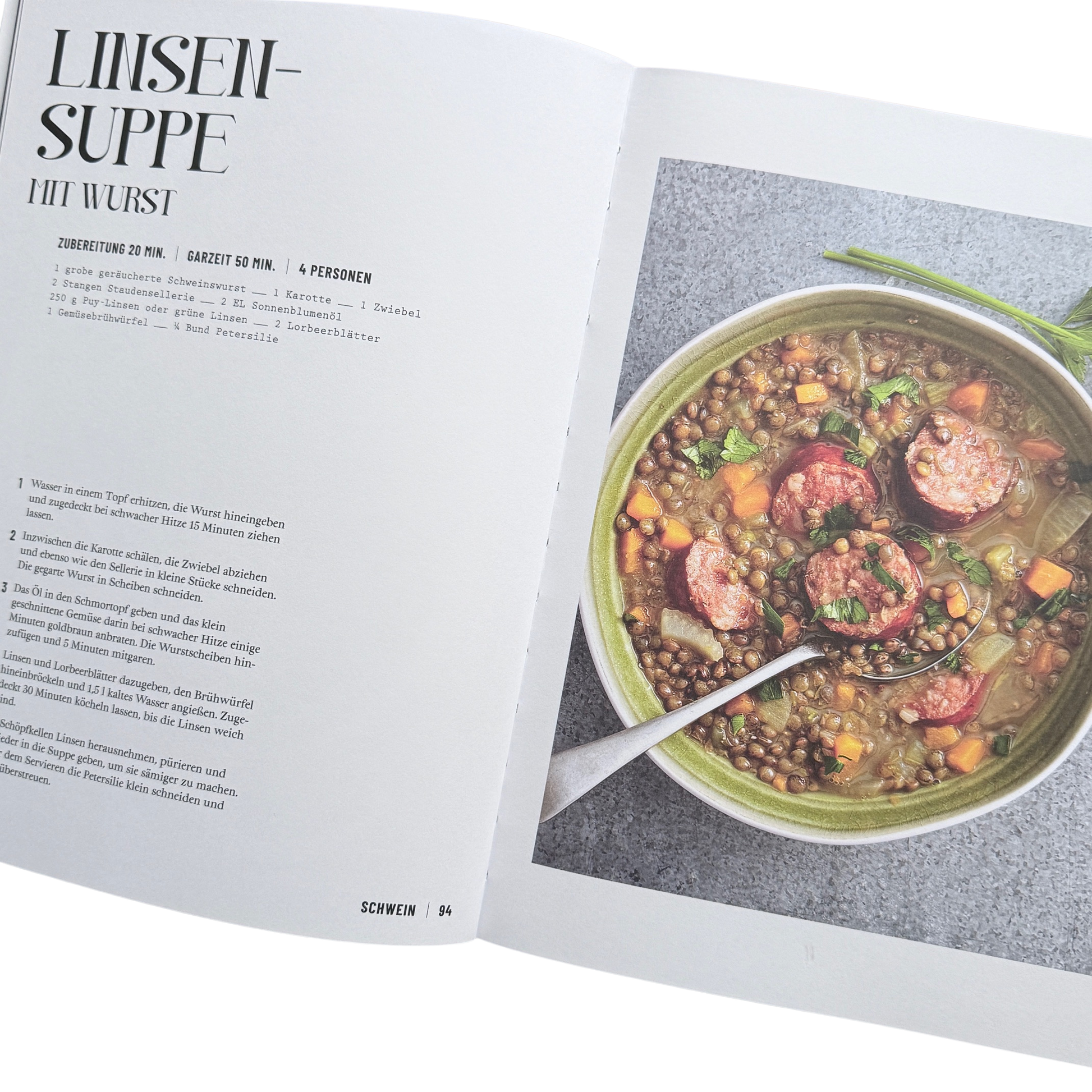 Kochbuch mit Schmortopfgerichten. Seite mit einem Linsensuppen Gericht. Ein Topf mit Linsen und Wurst darin. 