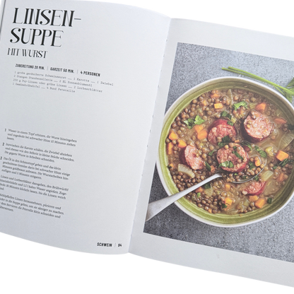 Kochbuch mit Schmortopfgerichten. Seite mit einem Linsensuppen Gericht. Ein Topf mit Linsen und Wurst darin. 