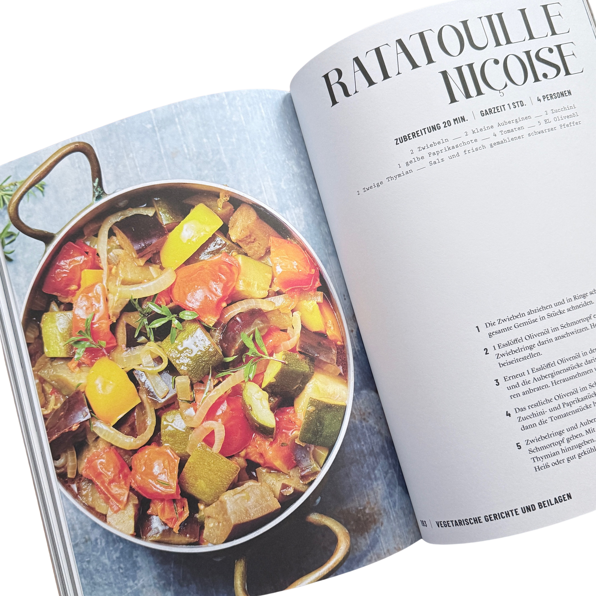Kochbuch mit Schmortopfgerichten. Seite mit einem Ratatouille Gericht. Ein Topf mit viel geschmortem Gemüse darin. 