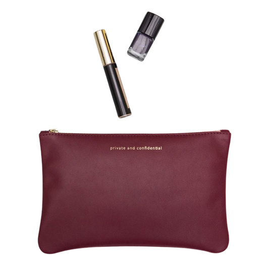Eine Ledertasche in burgund für Kosmetik mit Nagellack und Wimperntusche.