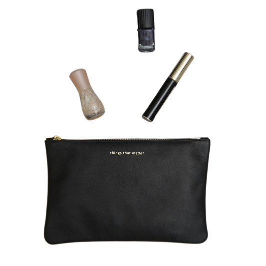 Eine schwarze Ledertasche mit Nagellack und Wimperntusche.