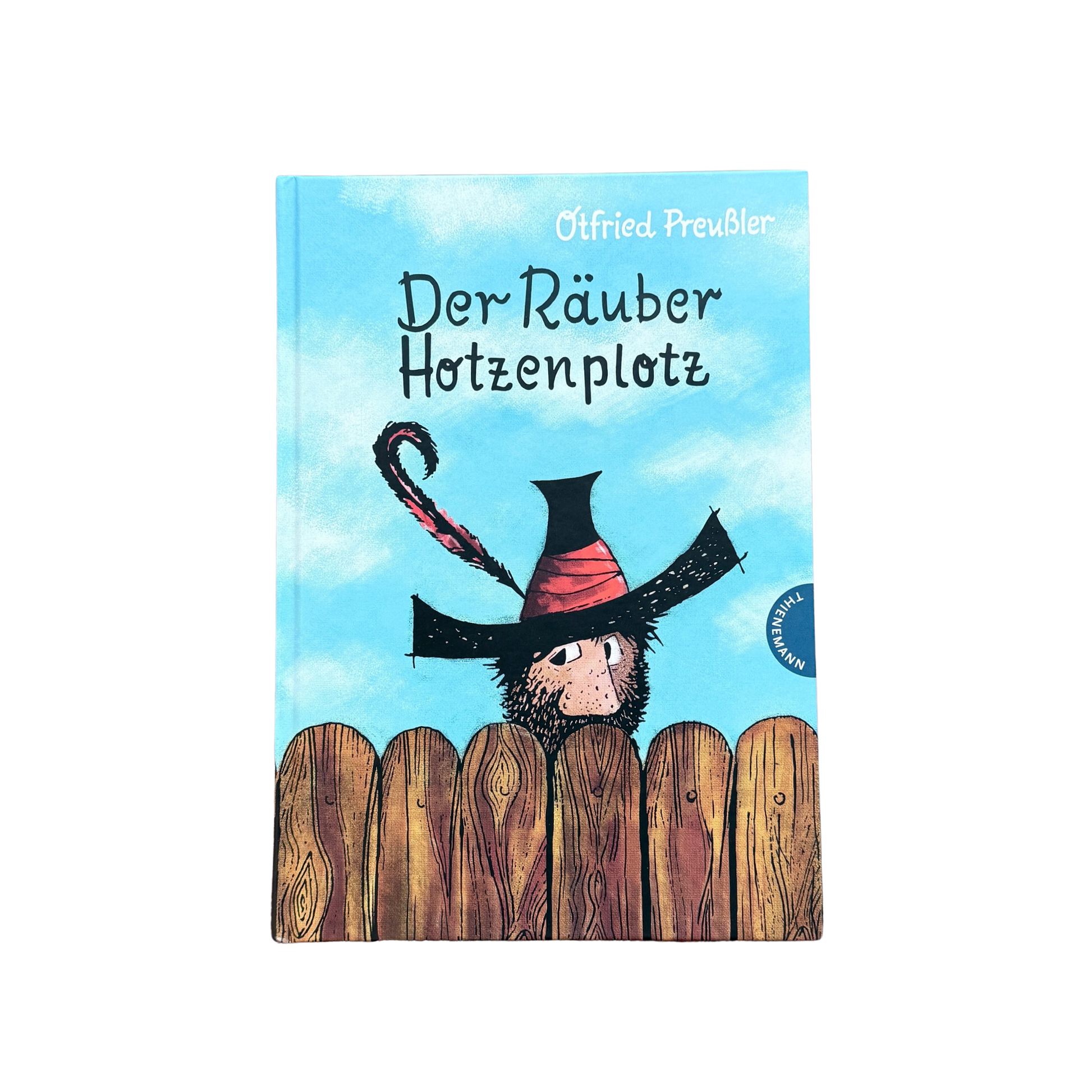 Der Räuber Hotzenpotz schaut über den Gartenzaun mit einem großen schwarzen Hut. 