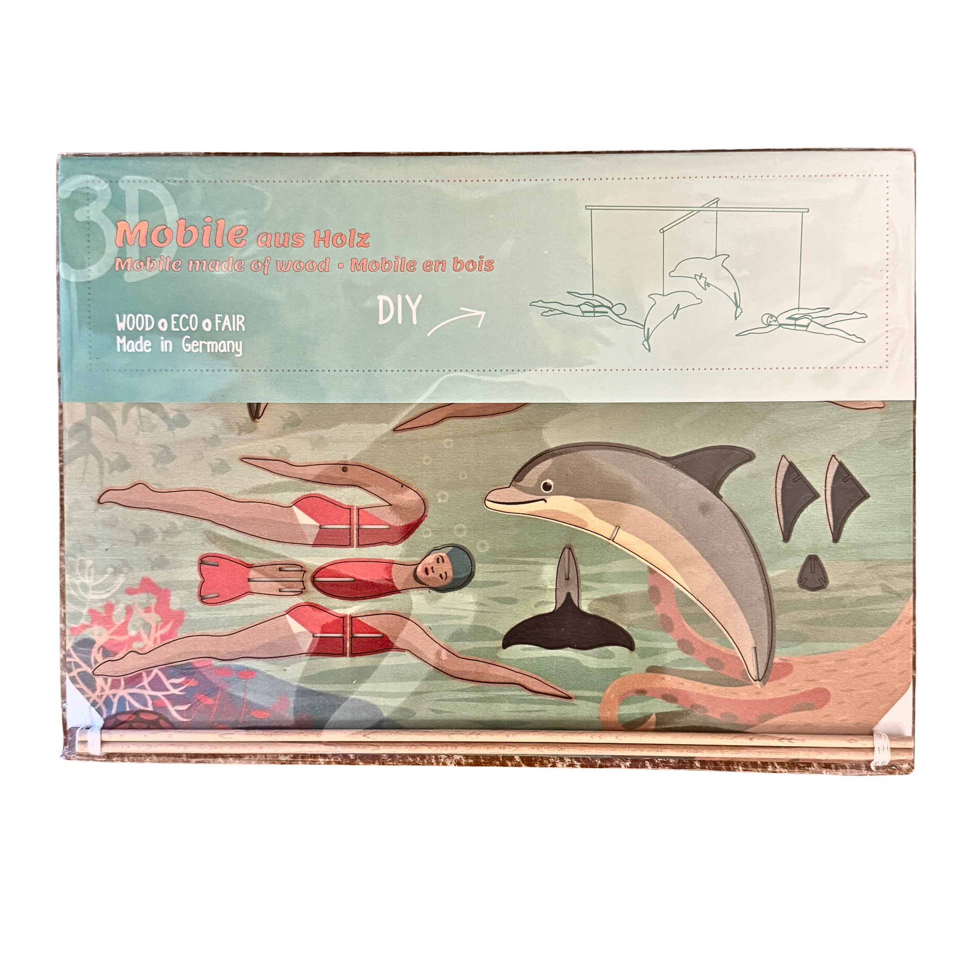 Ein Mobile Bastelset aus Holz mit zwei Schwimmerinnen und zwei Delfinen. Verpackung in Folie. 