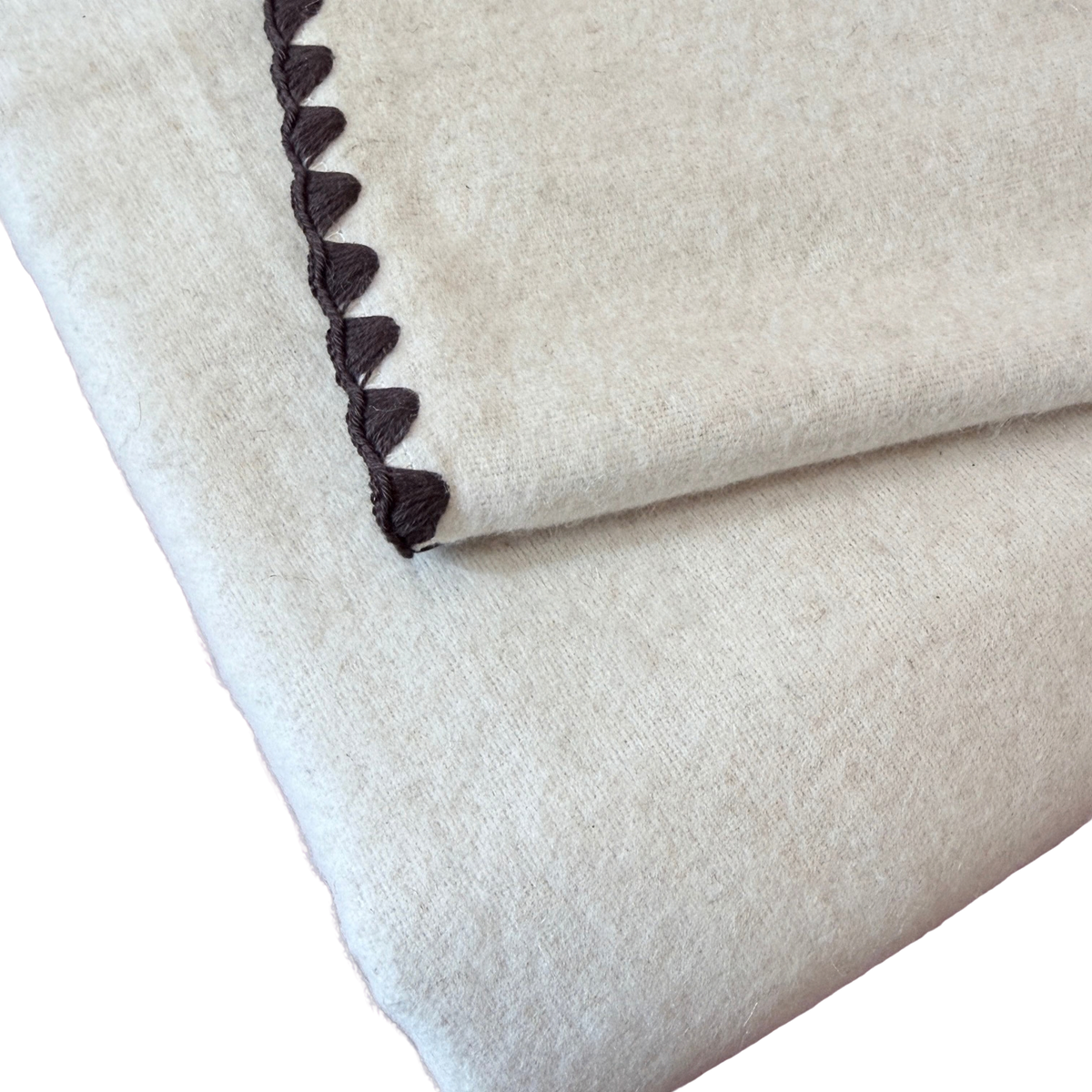 Kuscheldecke aus heller Baumwolle und Leinen mit einem braunen Zierrand.