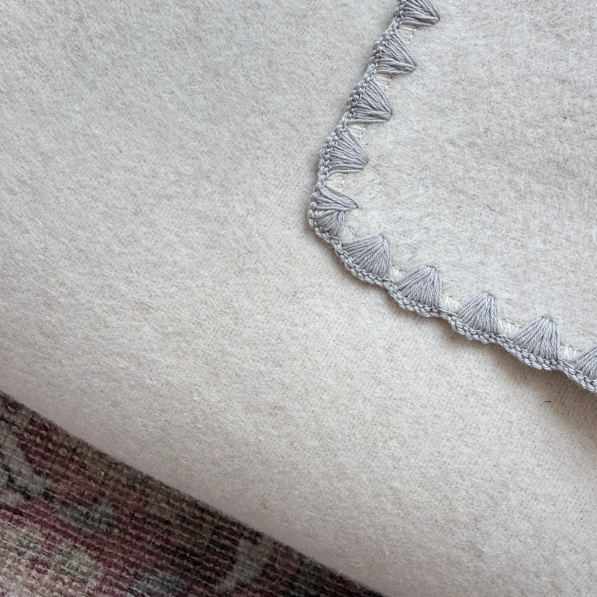 Kuscheldecke aus Baumwolle und Leinen in Beige mit einem grauen Zierrand.