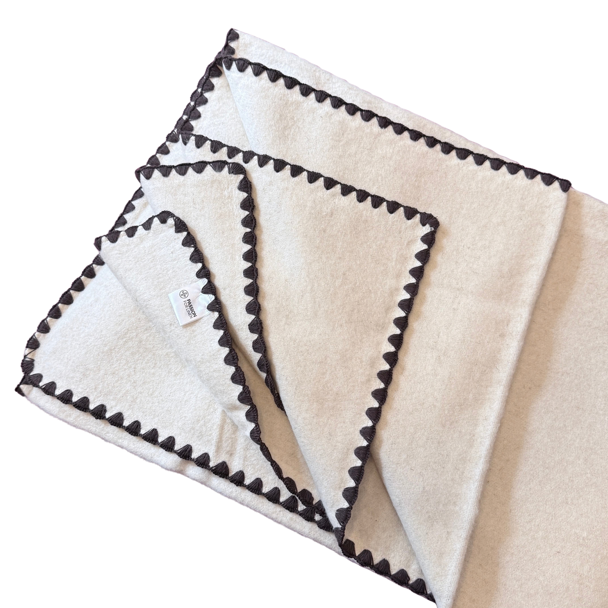 Kuscheldecke aus heller Baumwolle und Leinen mit einem braunen Zierrand.