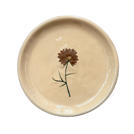 Kleiner Dekoteller in Puderrosa mit einer kleinen Blume als Dekor. 