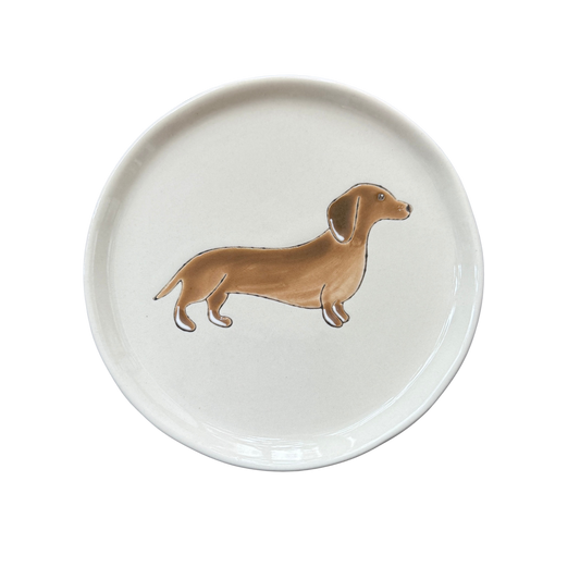 Kleiner Teller in Beige mit einme braunen Dackel als Dekor.
