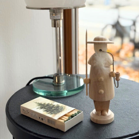 Räuchermann, lange Streichhölzer und Bauhaus Lampe auf dem Tisch stehend.