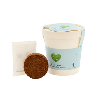 Saatgut, herzrasen kann man nicht mähen, ein Becher aus Pappe mit Gras-Saatgut welches aus dem Becher wächst. Inhalt.