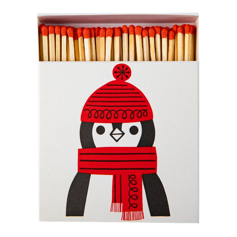 Quadratische Streichholzschachtel mit einem Pinguin mit roter Mütze und Schal darauf abgebildet. 