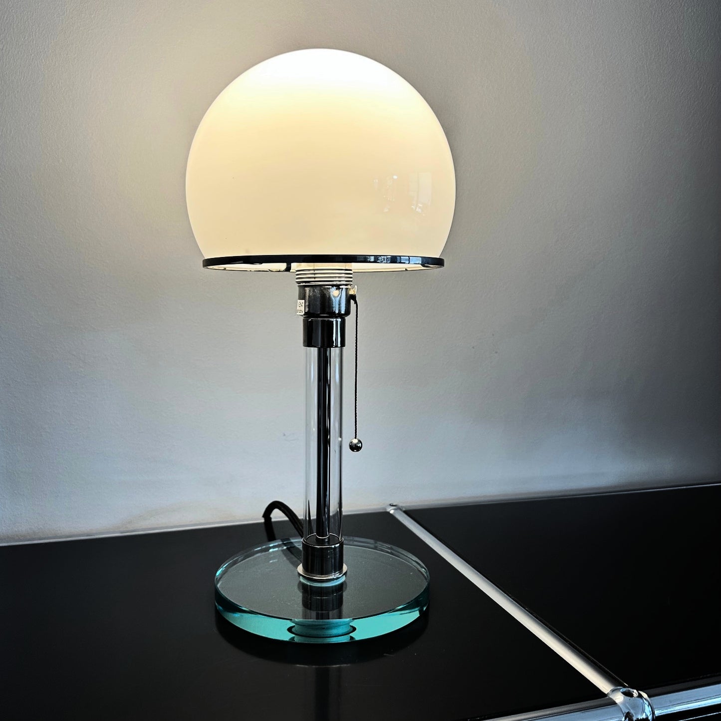 leuchtende bauhaus lampe mit glasfuss und glasschirm aus opalglas auf usm regal
