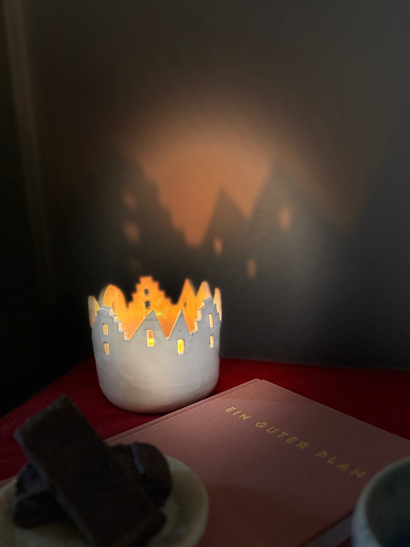 Ein weißes Windlicht aus Keramik mit Häusersilhouette.