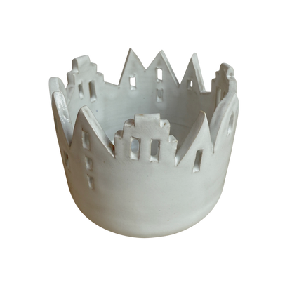 Ein weißes Windlicht aus Keramik mit Häusersilhouette.